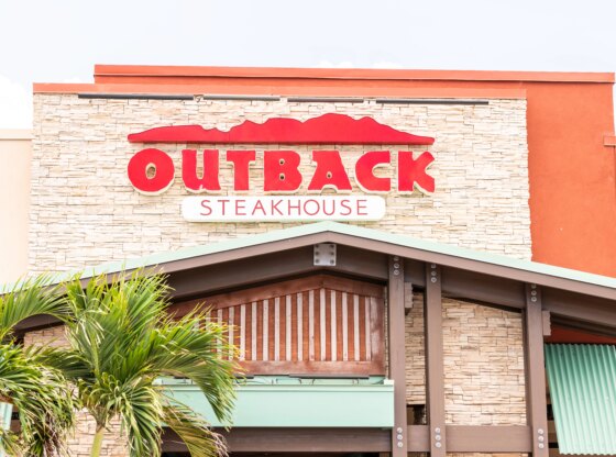 Outback steakhouse restaurant with red sign, logo architecture, entrance, facade, business storefront in Florida keys, palm trees