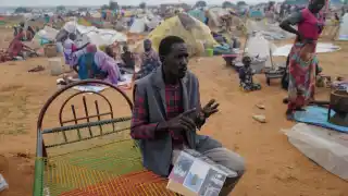 A man holds an album with photos of his son and father, killed by the FAR in west Darfur.