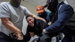 Agents from the Immigration and Customs Enforcement Service (ICE) and federal officials detain a migrant in the United States.