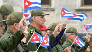 Cuban President Miguel Díaz-Canel waves a Cuban flag along with other people during a march in front of the US Embassy.
