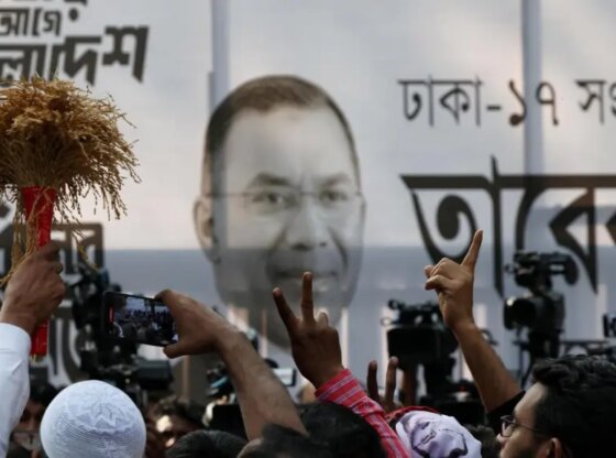 Supporters of the Bangladesh Nationalist Party (BNP) make the victory sign in front of a banner with the image of Tarique Rahman.
