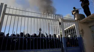 Members of the Syrian government's security forces stand guard as a group of female detainees gather at the al-Hol camp.