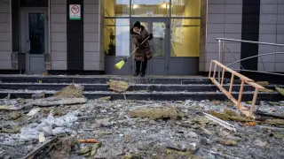 A woman sweeps up the rubble caused by a Russian attack on kyiv.